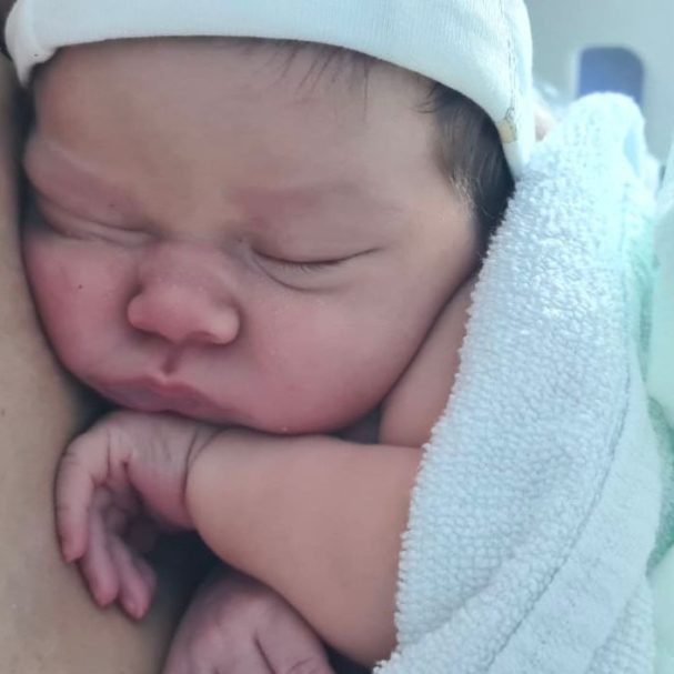 Recién nacida Bebé recién nacido durmiendo con una manta blanca y una gorra ligera.