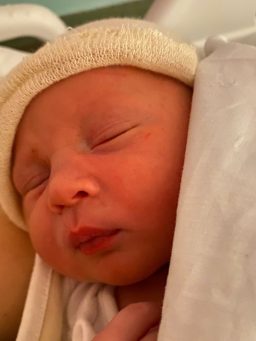 Recién nacido Bebé dormido envuelto en una manta, con gorro claro en la cabeza.