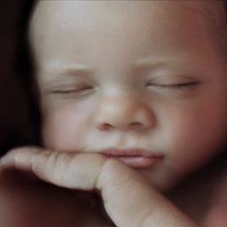 Ecografía 8K Bebé dormido con expresión serena y mano apoyada en la mejilla.